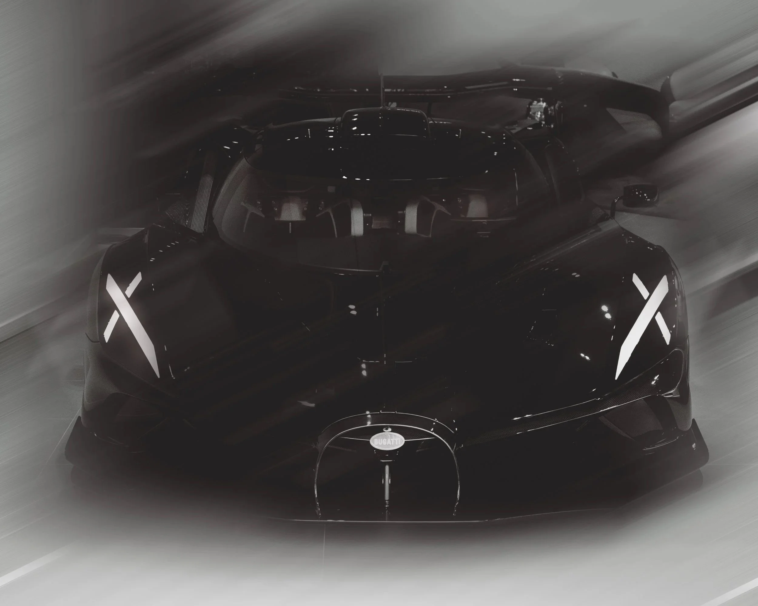 A sleek, black Bugatti Bolide supercar in motion with dynamic blurred streaks and illuminated X-shaped taillights.
