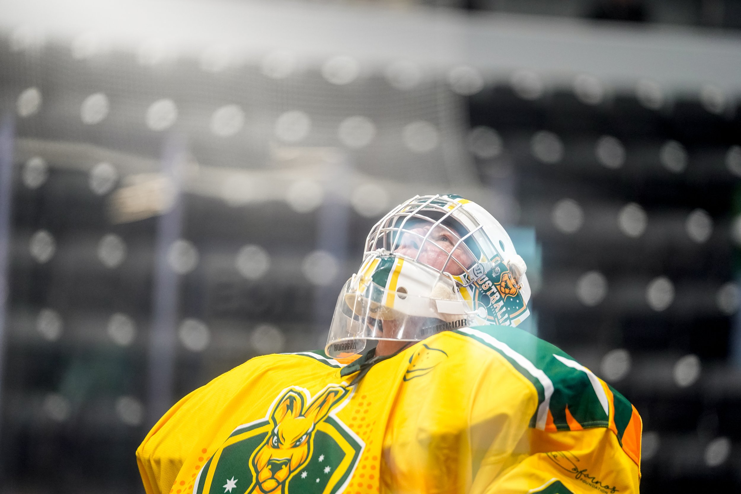 Australian Box lacrosse goalie in yellow jersey and helmet looking up on the ice rink at the World Box Lacrosse Tournament in Utica NY