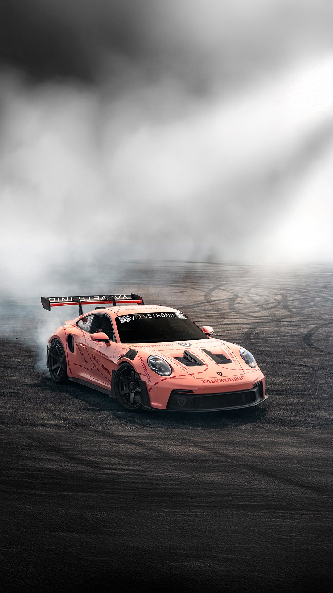 Valvetronic Porsche GT3rs drifting on a dark, smoky track with tire marks visible on the surface.